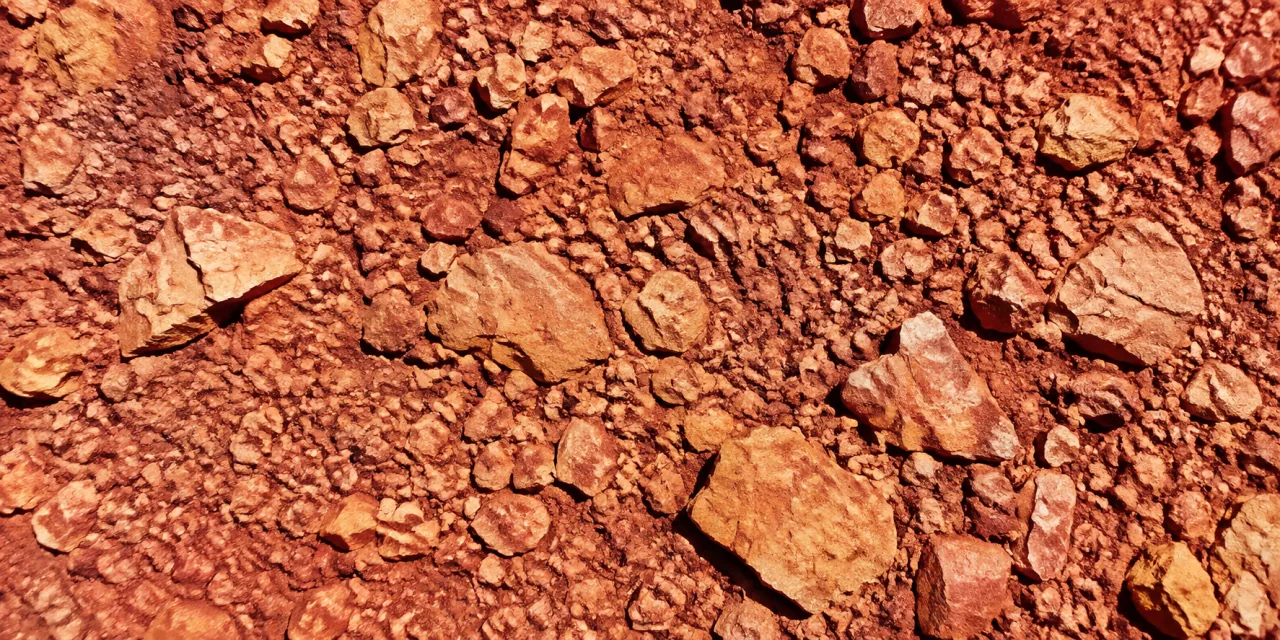 Gros plan d'un sol caillouteux rouge, éclats de pierre calcaire et gravier